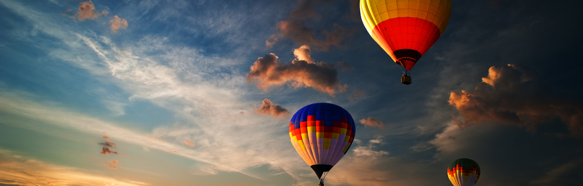 Three colourful hot air balloons flying at sunrise