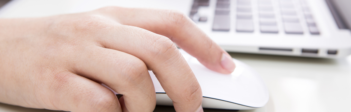 A person typing on a laptop keyboard and using a mouse.