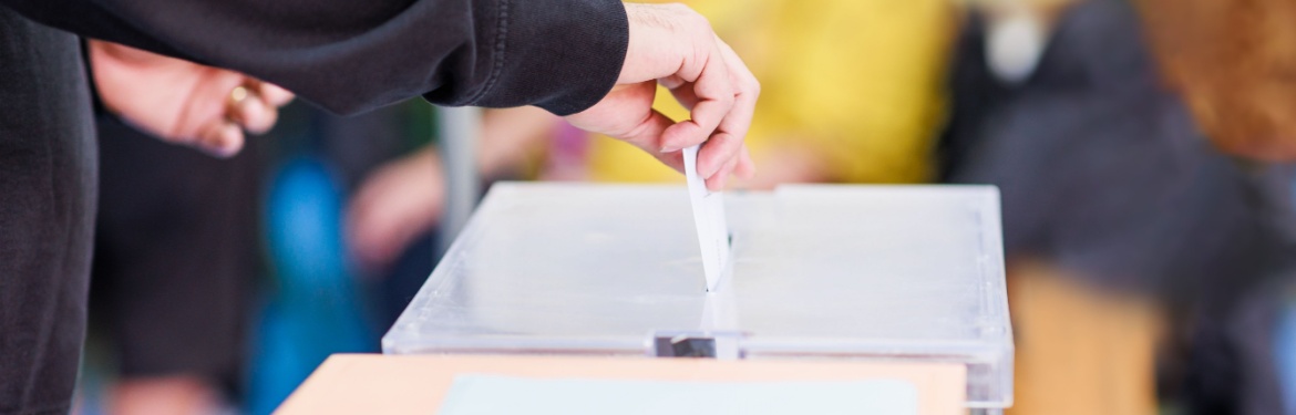 A man voting using a ballot box.