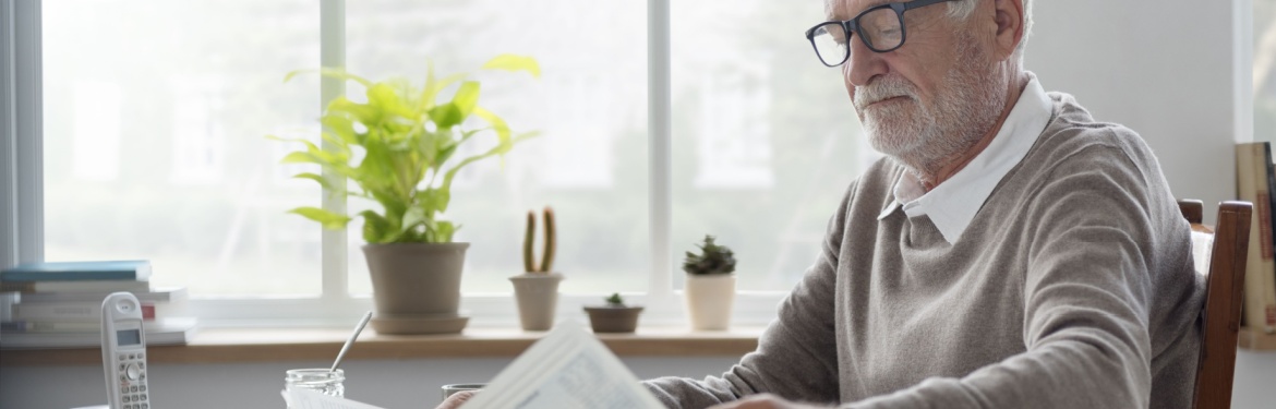 A man reading a newsletter at home.