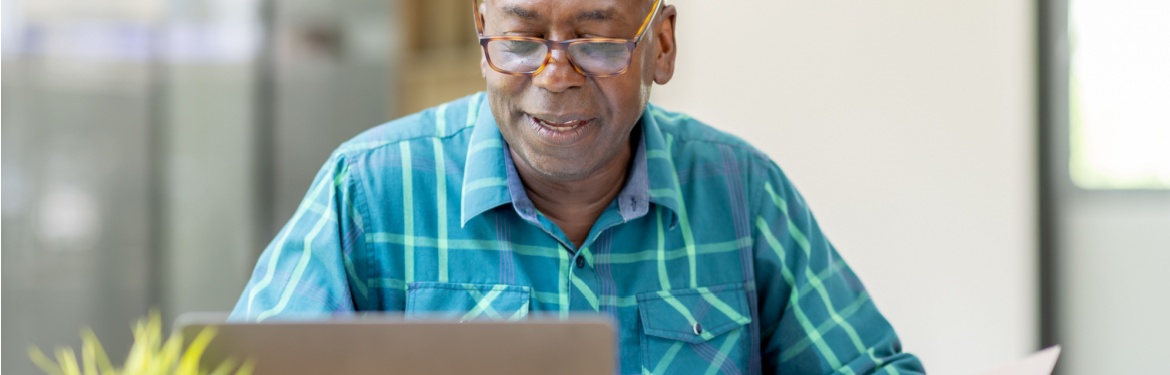 A man reviewing paperwork at his computer.