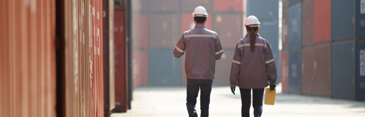 Two workers walking between shopping containers.