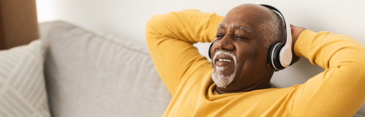 A man relaxing on a sofa with his hands behind his head.