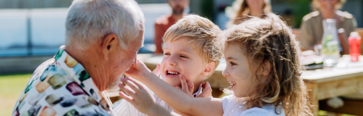 A grandfather playing with his grandchildren outdoors.