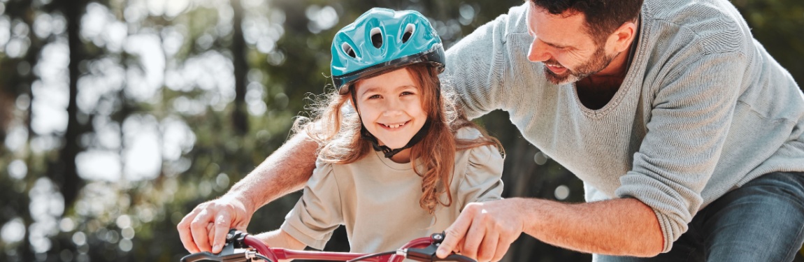 A father teaching his daughter to ride a bike.
