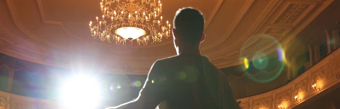 An actor rehearsing on a theatre stage.