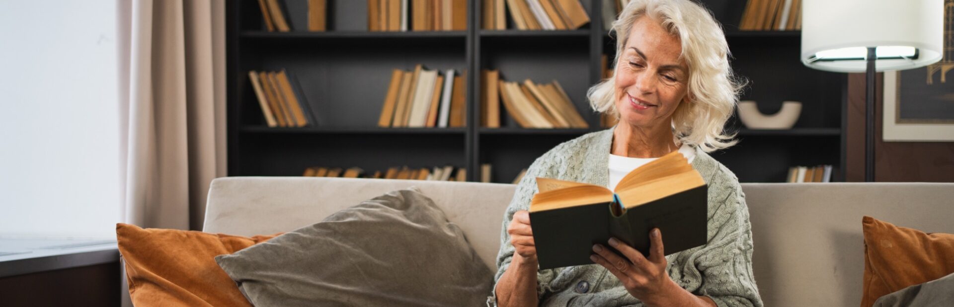 Smiling lady sitting on a sofa reading a book
