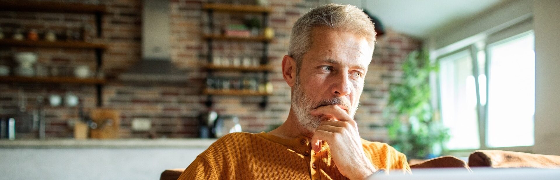 A man in his 50s thinking while using a laptop