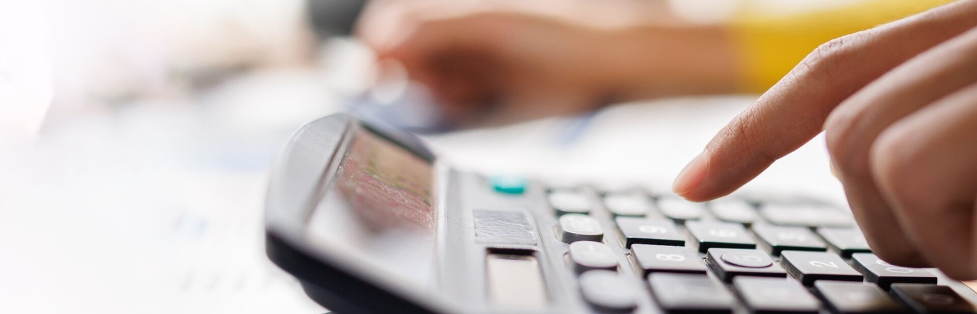 A person using a calculator while reviewing paperwork.